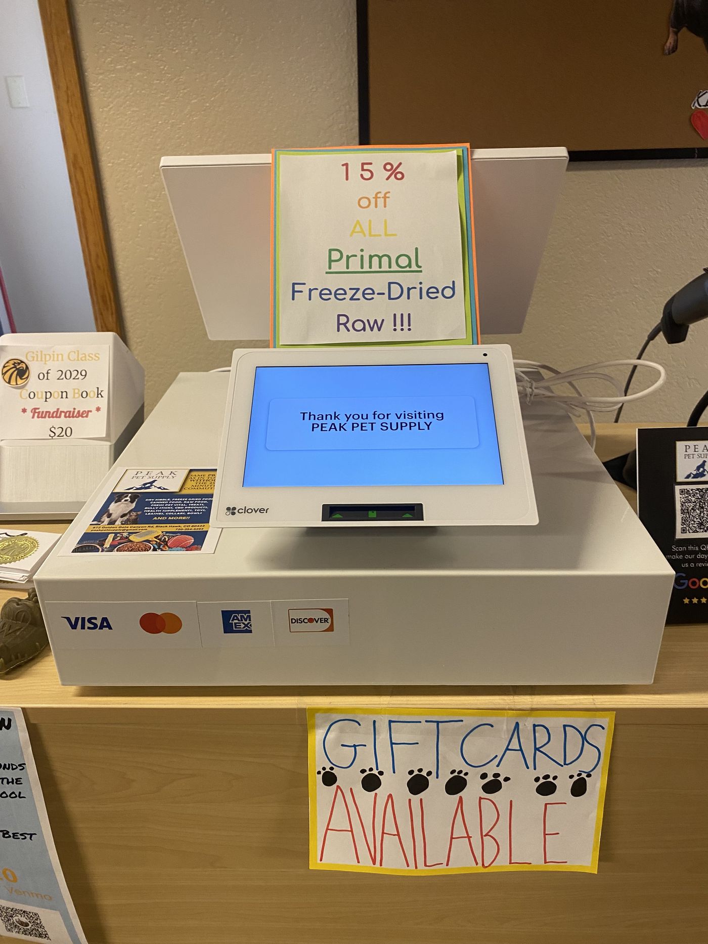 The Peak Pet Supply front counter — thank-you screen, handwritten deals, gift cards ready